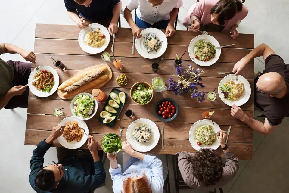 Friends around a full table, Greek catering, illustrative photo